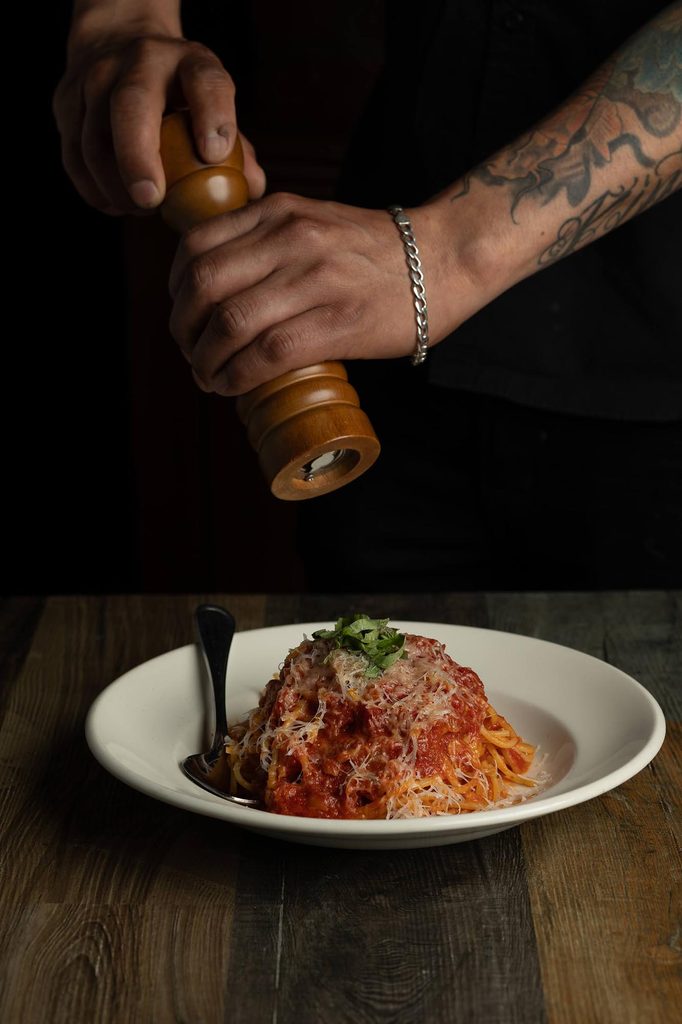 Chef seasoning pasta for restaurant photography