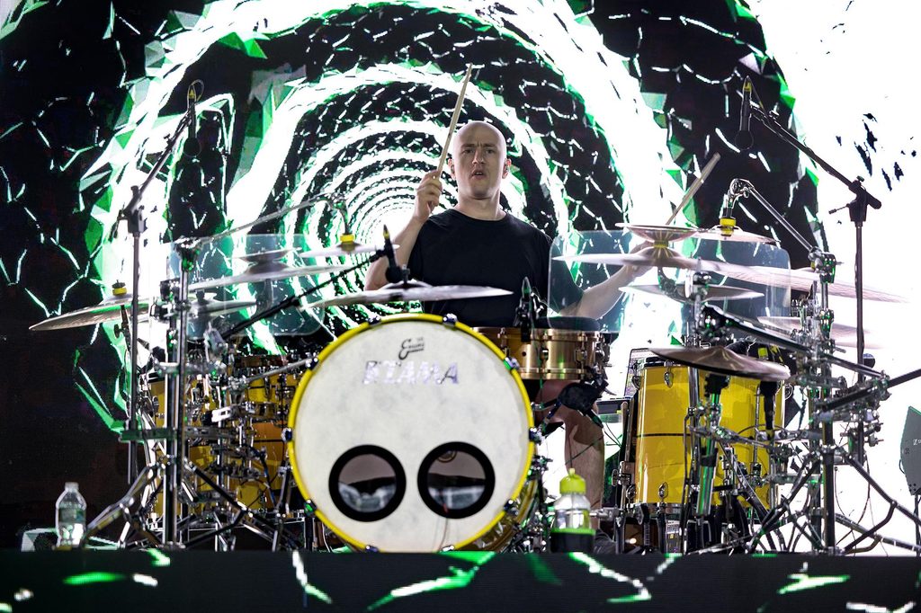 Drummer performing live with illuminated stage backdrop